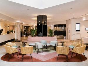 a lobby of a hotel with chairs and tables at Novotel Sydney International Airport in Sydney