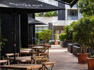 an outdoor patio with tables and chairs with an umbrella at Novotel Sydney International Airport in Sydney