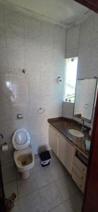 a bathroom with a toilet and a sink and a mirror at Pousada Peruibe in Peruíbe +30 photos