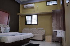 a bedroom with a bed and a couch and two windows at Athithi Bhawan in Godarpura