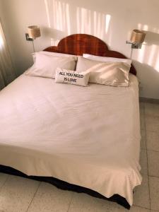 a white bed with a sign that reads all you need to love at Palermo facing Las Heras Park in Buenos Aires