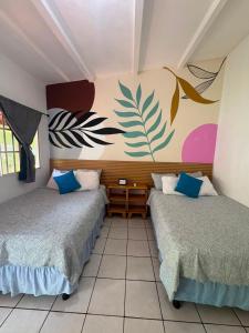 two beds in a room with a mural on the wall at The Beach Break Hotel El Cocal in Playa San Blas