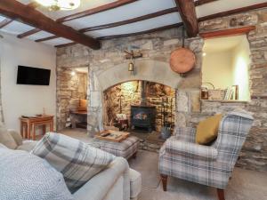 a living room with a stone fireplace and two chairs at Chamber End Fold in Skipton
