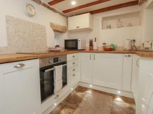 a kitchen with white cabinets and a microwave at Chamber End Fold in Skipton
