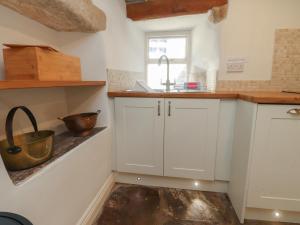 a kitchen with white cabinets and a sink at Chamber End Fold in Skipton +22 photos