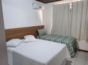 a hotel room with two beds and a chair at Guarajuba - casa em condomínio corais a 200 metros da praia in Camacari