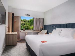 a hotel room with a large white bed and a window at ibis Rotorua in Rotorua