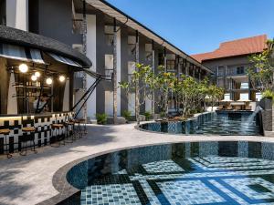 a hotel with a swimming pool and tables and chairs at Tribe Bali Legian in Legian