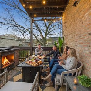 a group of people sitting on a patio with a fireplace at Luxe Chicago Retreat Game Room, Deck Fire Pit in Chicago