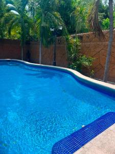 a large blue swimming pool with palm trees in the background at Las Brisas House, Manzanillo in Manzanillo