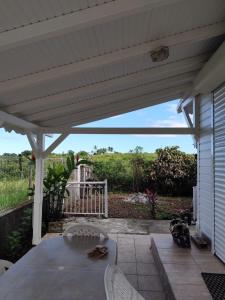 a white pergola with a table and chairs on a patio at Studio spacieux au calme in Capesterre