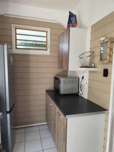 a small kitchen with a microwave and a refrigerator at Studio spacieux au calme in Capesterre