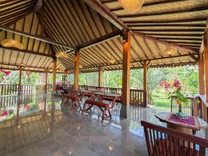 a large pavilion with tables and chairs and trees at Pondok Risky in Tegalalang