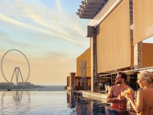 a man and a woman standing in the pool at a resort at Sofitel Dubai Jumeirah Beach in Dubai