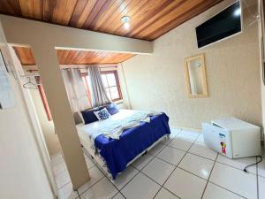 a bedroom with a bed with blue sheets and a tv at Pousada Azul do Mar by BlueOcean in Arraial do Cabo
