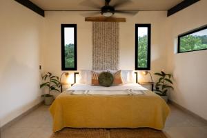 a bedroom with a bed with a yellow blanket and windows at Somni Hill in Torio