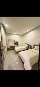 a bedroom with two beds and a table in it at Bohovibes in Buraydah