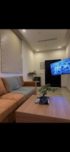 a living room with a couch and a large flat screen tv at Bohovibes in Buraydah