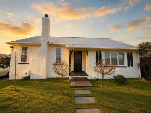 a white house with a chimney and two trees in the yard at Maison Millie - Central Pet-Friendly Sleeps 4 in Rotorua