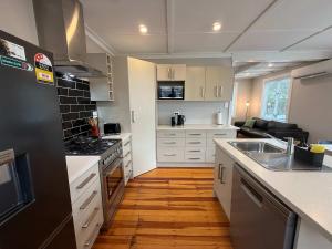 a kitchen with white cabinets and a black refrigerator at Maison Millie - Central Pet-Friendly Sleeps 4 in Rotorua