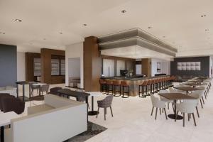 a restaurant with a bar and tables and chairs at AC Hotel Lenexa City Center in Lenexa