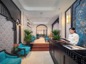 a woman standing at a counter in a hotel lobby at Ritana Boutique Hotel & Spa in Hanoi