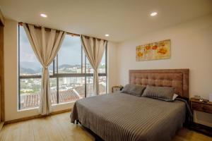 a bedroom with a bed and a large window at HOSTARA EDIFICIO CAPITALIA, El Cable, Manizales in Manizales