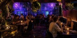a group of people sitting at tables in a room with purple lighting at Eywa Retreat in Uluwatu +61 photos