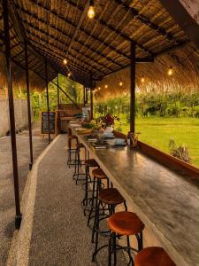 a long bar with wooden stools in an outdoor restaurant at Dewi Teduh Villa in Sidemen