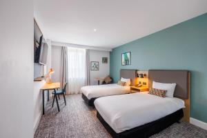 a hotel room with two beds and a desk at Holiday Inn Stevenage by IHG in Stevenage +119 photos