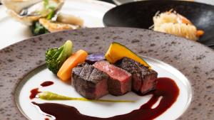 a plate of food with meat and vegetables on a table at ホテルドゥアッシュ in Kushiro