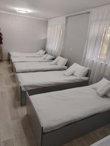 a row of beds in a room with white curtains at Sayora Guest House in Khorugh +2 photos