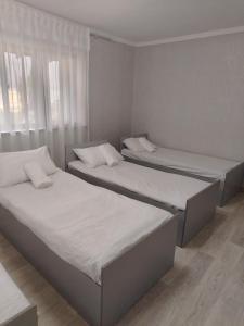 two beds in a room with white sheets at Sayora Guest House in Khorugh