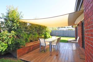 a patio with a table and chairs under an umbrella at Plovers Rest in Inverloch