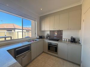 a kitchen with white cabinets and a large window at Sandpiper 10 - Close to Town and Beach in Inverloch