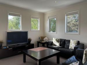 a living room with a couch and a flat screen tv at Sandpiper 10 - Close to Town and Beach in Inverloch