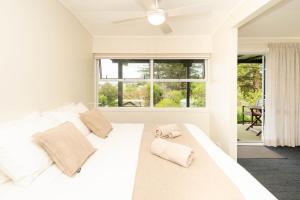 a bedroom with a white bed with two towels on it at Cascade Garden Apartments in Burnt Pine