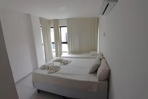 a white bedroom with two beds and a window at Condomínio Pérola de Porto in Ipojuca +46 photos