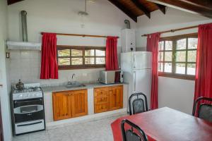 a kitchen with a white refrigerator and red curtains at Cabañas Costa Alta in Mina Clavero