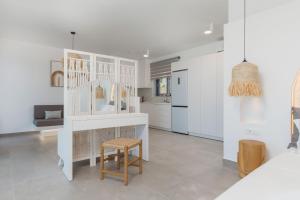 a white kitchen with a table and a stool at Zante Fiore Suites in Xirokástellon