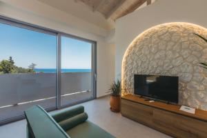 a living room with a tv and a large window at Zante Fiore Suites in Xirokástellon