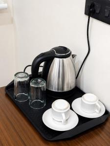 a tea kettle and glasses on a black tray at Hotel Lavish Grand in Tenāli