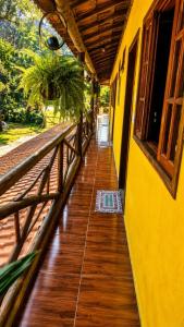 a hallway of a yellow building with a wooden floor at Refúgio do Paraty Mirim in Paraty +1 photo