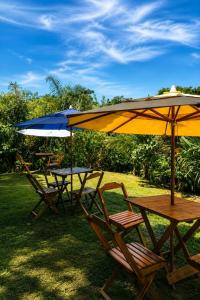 two tables and chairs with umbrellas on the grass at Refúgio do Paraty Mirim in Paraty