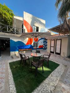a patio with a table and chairs and an umbrella at Hotel El Emigrante in Puerto Colombia