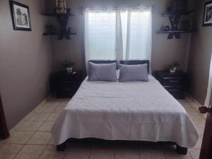 a bedroom with a bed with white sheets and a window at Hospedaje Ejecutivo Toronjal II in La Ceiba