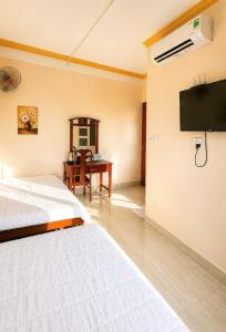 a bedroom with a bed and a desk and a tv at Trung Hậu Hotel Côn Đảo in Con Dao