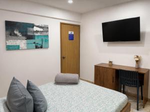 a bedroom with a bed and a flat screen tv at HOTEL BELEN-La Flora- Cali Valle del Cauca in Cali