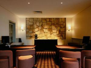 a restaurant with tables and chairs and a stone wall at Mercure Clear Mountain Lodge in Mount Samson