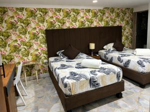 a bedroom with two beds and a wall with flowers at HOTEL BELEN-La Flora- Cali Valle del Cauca in Cali